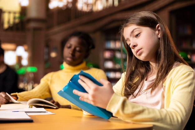 Jugendliche konzentrieren sich auf das Lesen der erforderlichen Bücher an einem Schreibtisch
