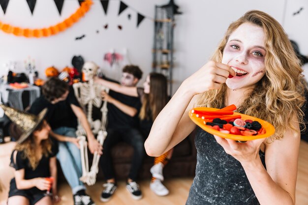 Jugendliche mit dem Zombiemake-up und orange Platte, die Marmelade essen