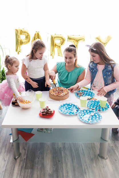 Jugendliche und Kinder, die Kuchen schneiden