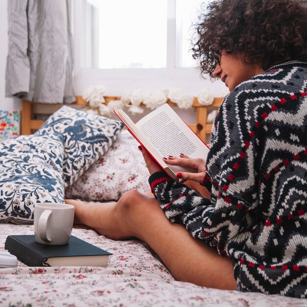 Jugendlicher, der das Lesen auf Bett genießt