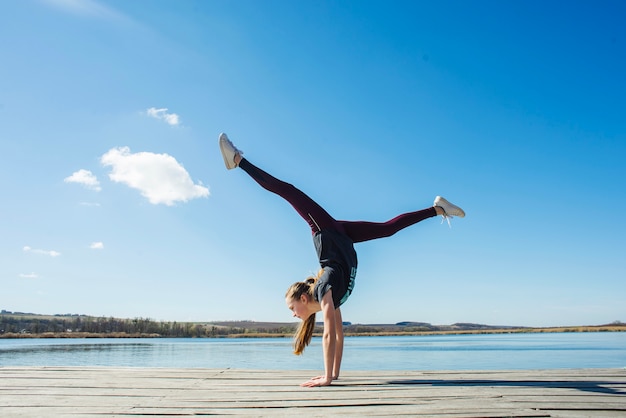 Jugendlicher, der Handstand nahe Wasser durchführt