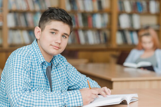 Jugendlicher, der Hausarbeit in der Bibliothek tut