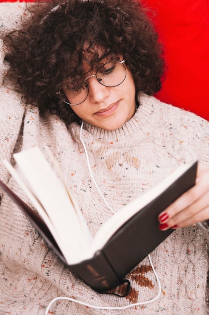 Jugendlicher, der Musik hört und Buch liest