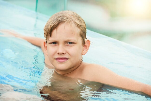 Jugendlicher Junge, der im Swimmingpool stillsteht