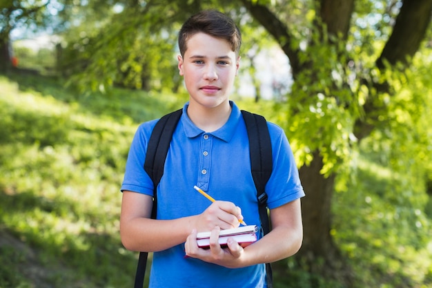 Jugendlicher Junge, der in Notizbuch schreibt