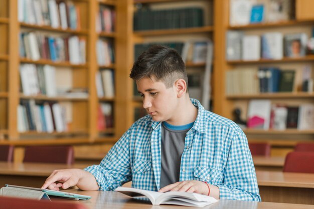 Jugendlicher mit Buch unter Verwendung der Tablette