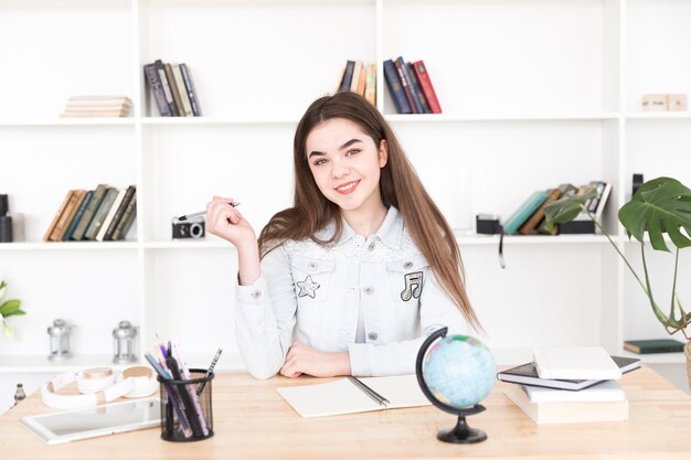 Jugendstudent, der bei Tisch mit Stift in den Händen sitzt