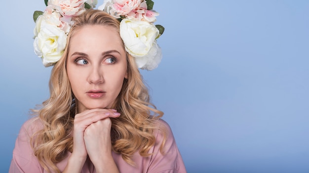 Junge ängstliche blonde Dame mit schönem Blumenkranz