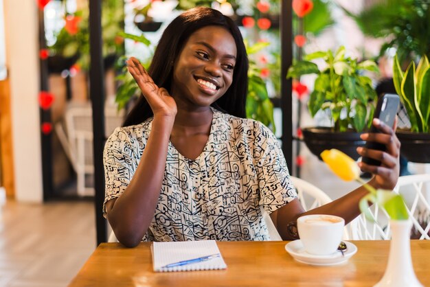 Junge afrikanische Frau, die ein selfie im Kaffeegeschäft nimmt