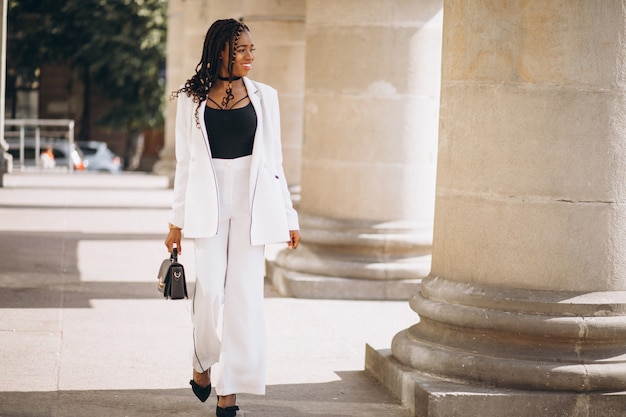 Junge afrikanische Frau kleidete im weißen Anzug außerhalb der Straße an