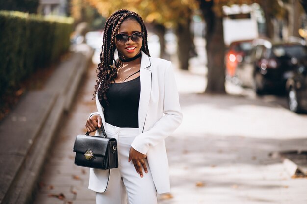 Junge afrikanische Frau kleidete im weißen Anzug außerhalb der Straße an
