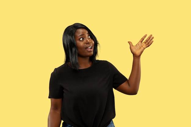 Junge Afroamerikanerfrau lokalisiert auf gelbem Gesichtsausdruck