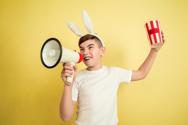 Junge als Osterhase auf gelber Wand