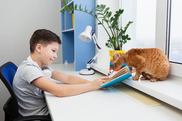 Kostenloses Foto junge am schreibtisch mit katzenlesung