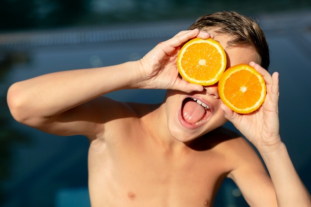 Junge am Schwimmbad mit Zitrusfrüchten