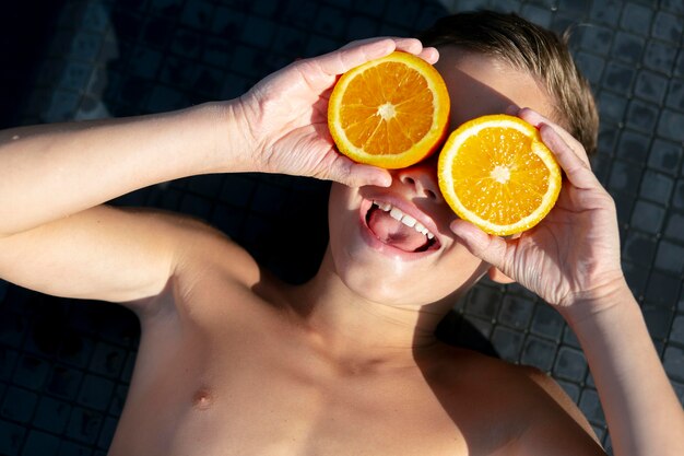 Junge am Schwimmbad mit Zitrusfrüchten