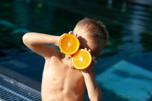 Junge am Schwimmbad mit Zitrusfrüchten