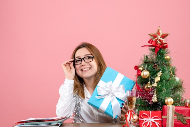 junge Arbeiterin hält Geschenk auf rosa