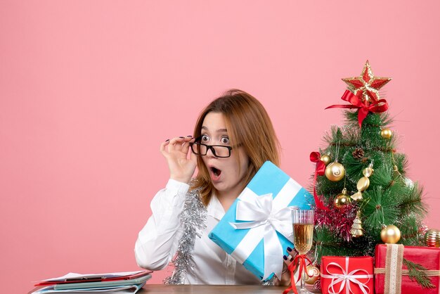 junge Arbeiterin hält Geschenk auf rosa