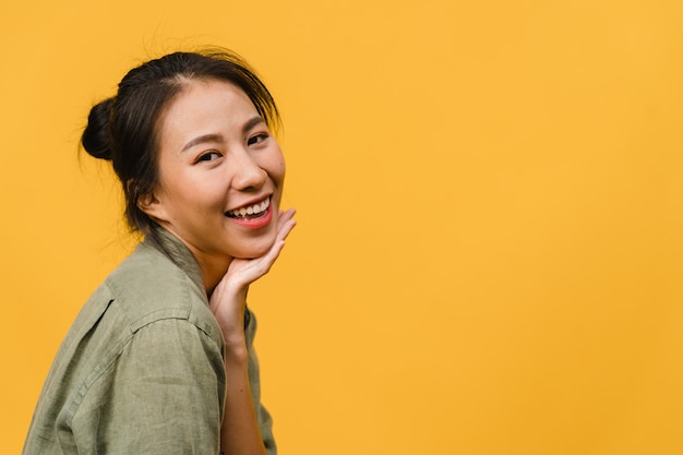 Junge asiatische Dame mit positivem Ausdruck, breites Lächeln, gekleidet in Freizeitkleidung über gelber Wand. Glückliche entzückende frohe Frau freut sich über Erfolg. Gesichtsausdruck Konzept.