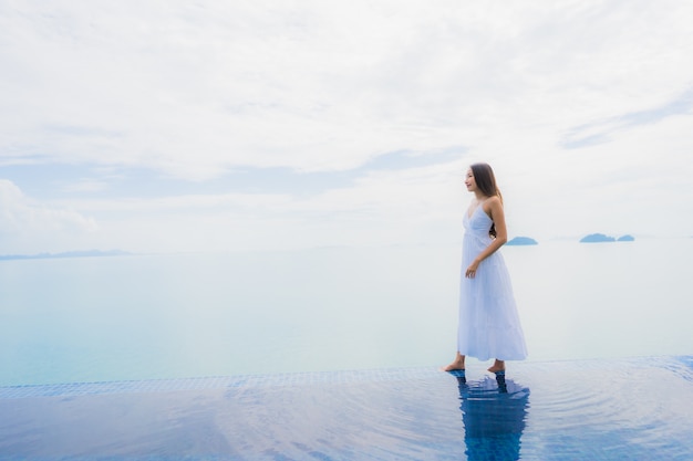 Junge asiatische Frau des Porträts entspannen sich das Lächeln, das um Swimmingpool im Hotel und im Erholungsort glücklich ist