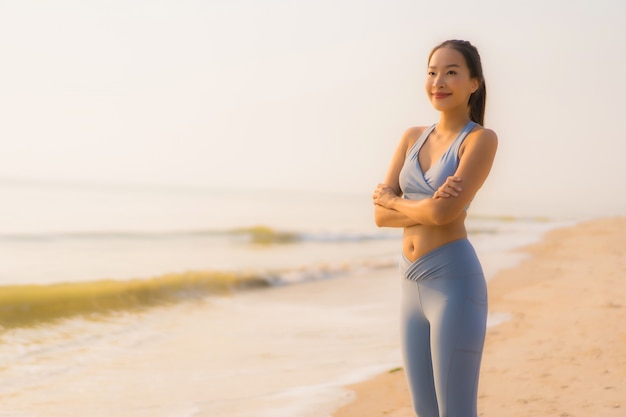 Junge asiatische Frau des Porträtsports bereiten Übung vor oder laufen auf dem Strandseeozean