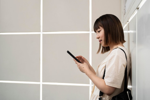 Junge asiatische Frau, die draußen ihr Telefon überprüft
