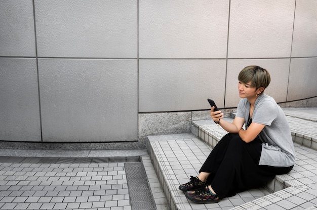 Junge asiatische Frau, die draußen ihr Telefon überprüft