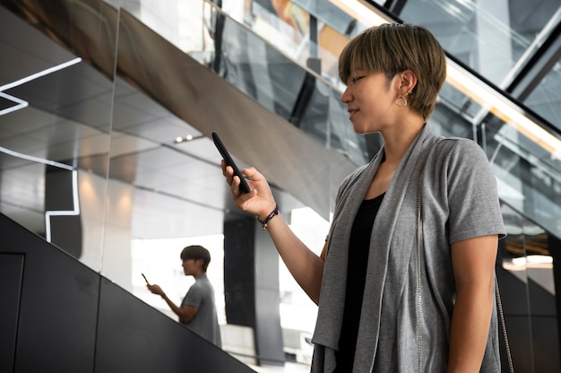 Junge asiatische Frau, die ihr Telefon überprüft