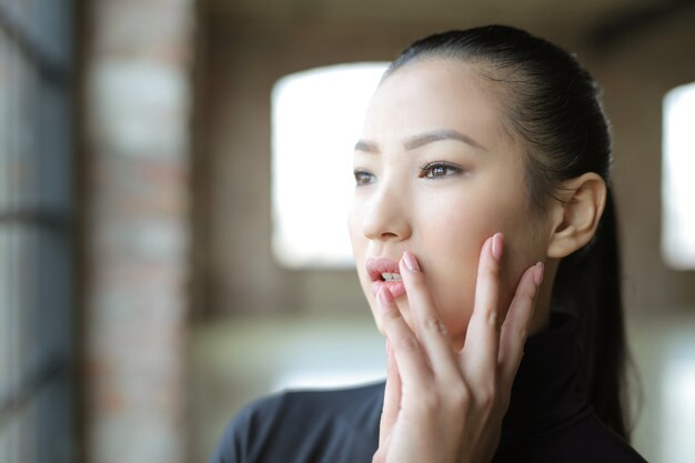 Junge asiatische Frau, die tagsüber aus dem Fenster schaut