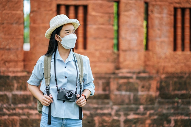 Junge asiatische Rucksacktouristin mit Hut und Schutzmaske auf Reisen in historischer Stätte