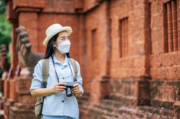 Junge asiatische Rucksacktouristin mit Hut und Schutzmaske auf Reisen in historischer Stätte