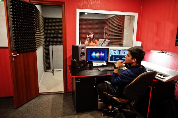 Junge asiatische sängerin mit mikrofonaufnahmelied im plattenmusikstudio mit tonproduzent