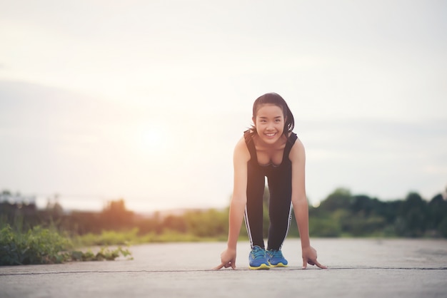 Junge Athletenfrau ist bereit, Lauf zu beginnen oder zu rütteln