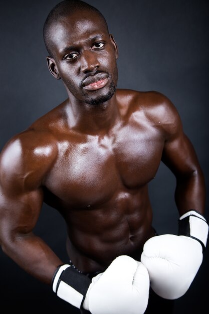 Junge athletischen Boxer tragen Handschuhe in schwarzem Hintergrund.