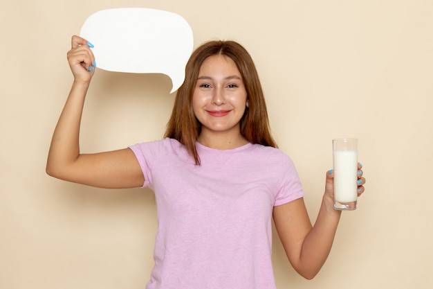 Junge attraktive Frau der Vorderansicht im rosa T-Shirt und in den blauen Jeans, die Milch und Zeichen halten