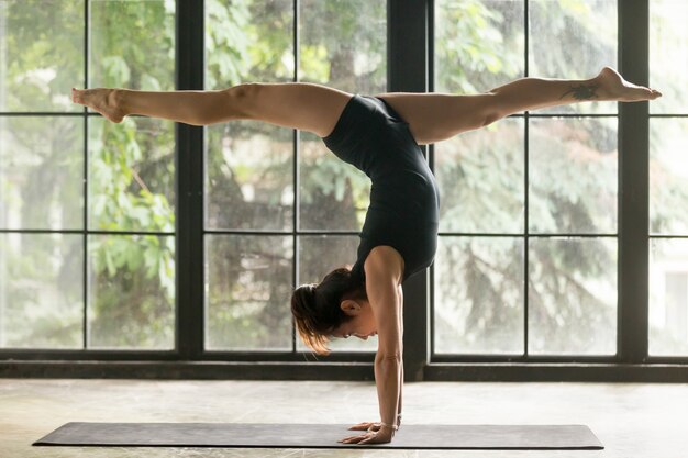 Junge attraktive Frau in der Handstandhaltung, Haupthintergrund