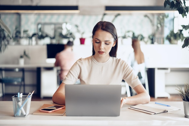 Junge attraktive Geschäftsfrau, die am Laptop im Büro arbeitet