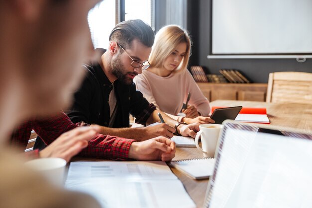 Junge attraktive Kollegen, die im Büro sitzen und arbeiten.