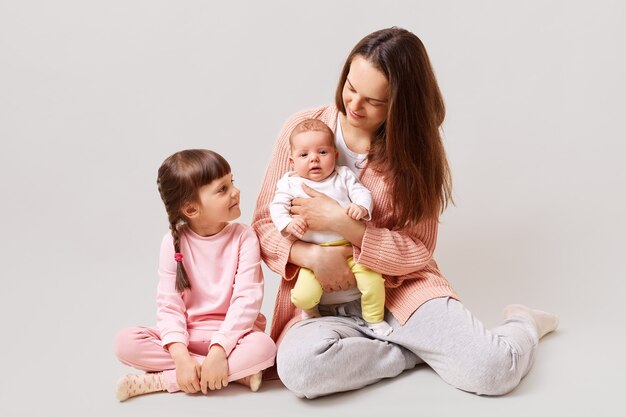 Junge attraktive Mutter zwei Töchter, die auf Boden sitzen