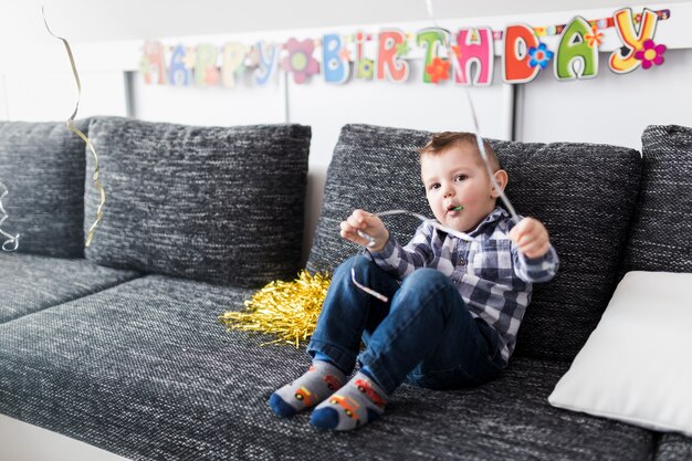 Junge auf dem Sofa, das Kamera betrachtet