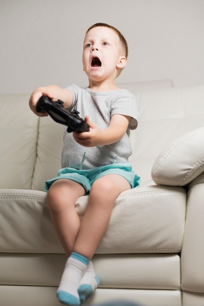 Junge auf der Couch, die digitale Spiele spielt