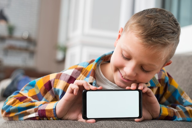 Junge auf der Couch, die Smartphoneschirm zeigt