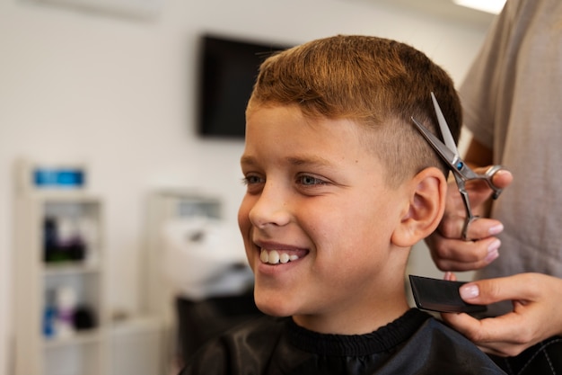 Kostenloses Foto junge bekommt haarschnitt bei seitenansicht des salons