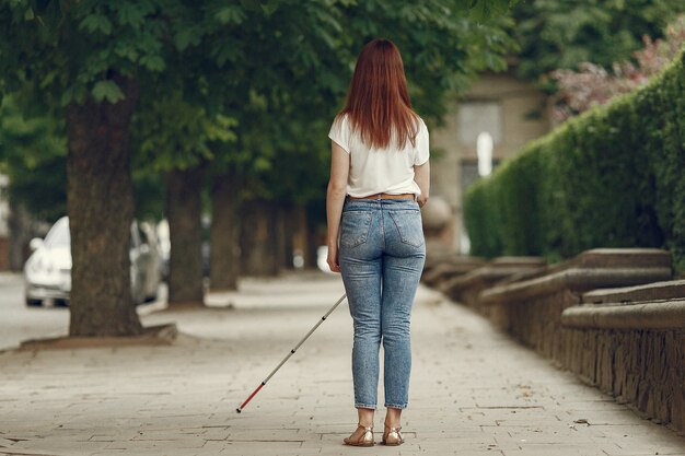 Junge blinde Person mit langem Stock, der in einer Stadt geht