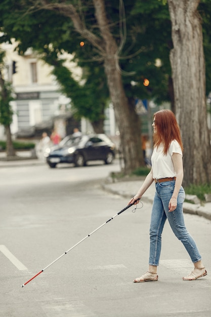 Kostenloses Foto junge blinde person mit langem stock, der in einer stadt geht