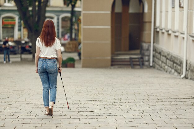 Junge blinde Person mit langem Stock, der in einer Stadt geht