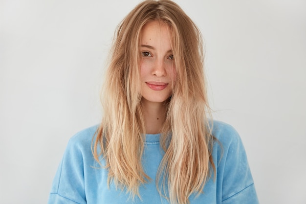 Junge blonde Frau, die blauen Pullover trägt