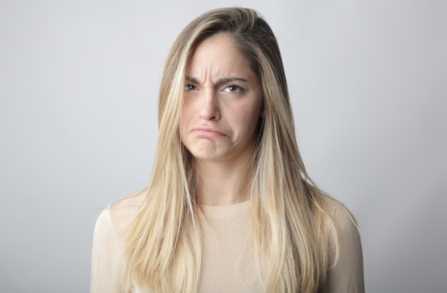 Junge blonde Frau, die ein Gesicht der Unsicherheit und des Zweifels zeigt