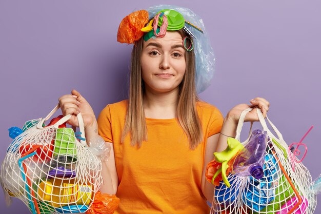 Junge blonde Frau, die mit Plastikmüll aufwirft